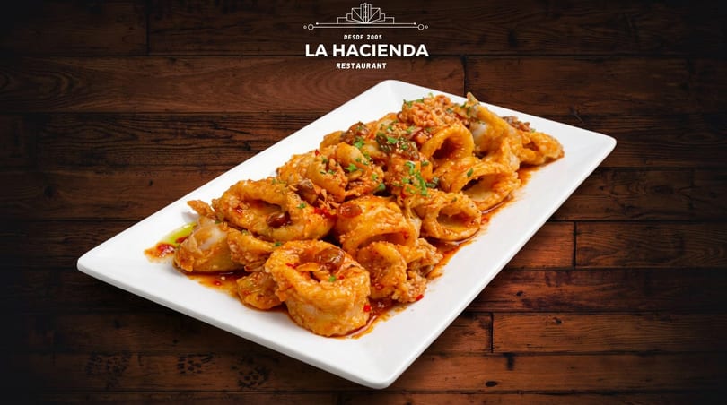 Plate of La Hacienda's fried calamari rings with a savory sauce and herbs.